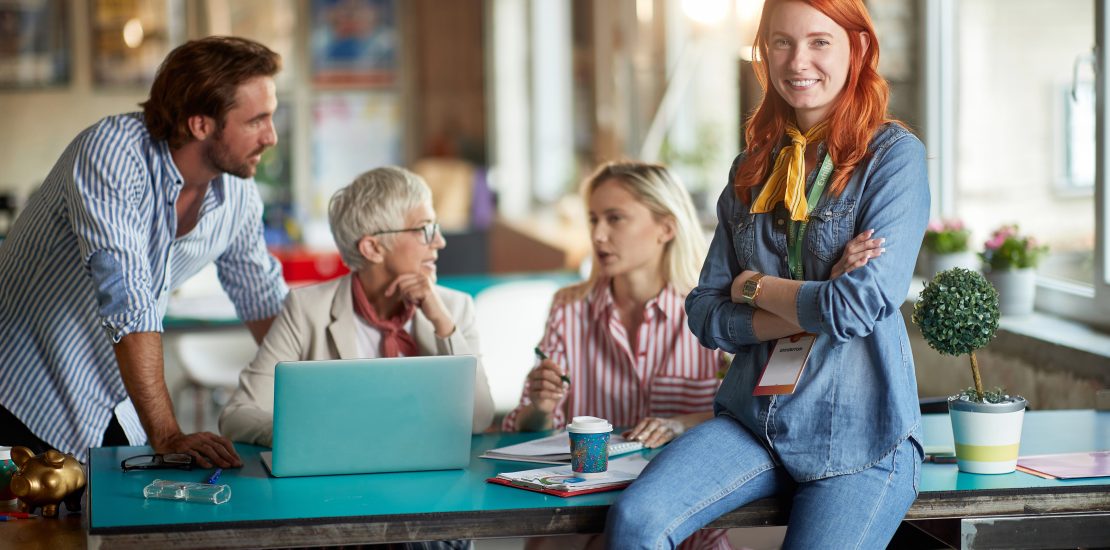 A young beautiful woman is posing for a photo while enjoying a work with her colleagues in a relaxed atmosphere in the office